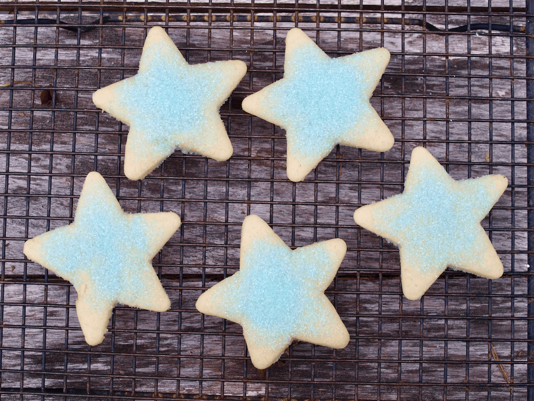 Five star-shaped cookies rest on a cooling rack.